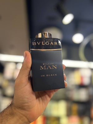 a person holding a black bottle of perfume