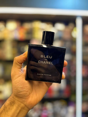 a hand holding a bottle of perfume in a store