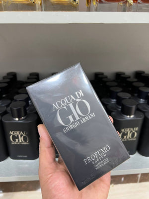 a hand holding a box of perfume in a store