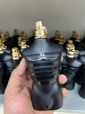 a hand holding a black bottle of perfume