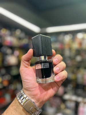 a hand holding a bottle of perfume in a store