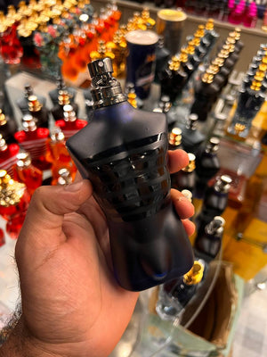 a hand holding a black bottle of perfume