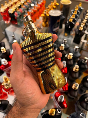 a hand holding a gold colored perfume bottle