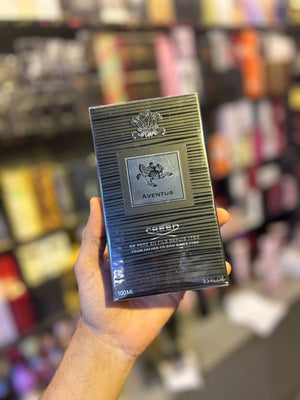 a person holding a box of perfume in a store