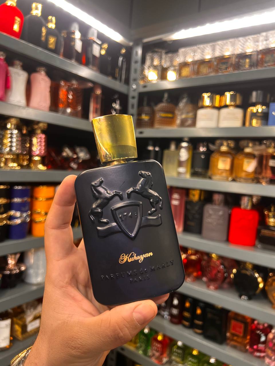 a person holding a black and gold perfume bottle in a store
