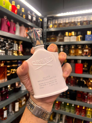 a hand holding a bottle of perfume in a store