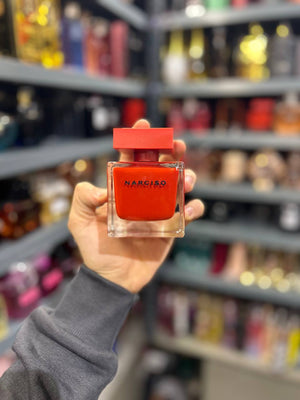 a person holding up a small bottle of perfume