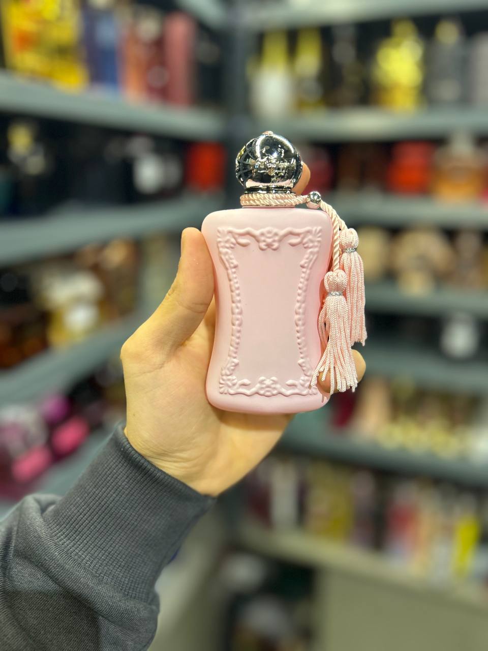 a person holding a pink perfume bottle in a store