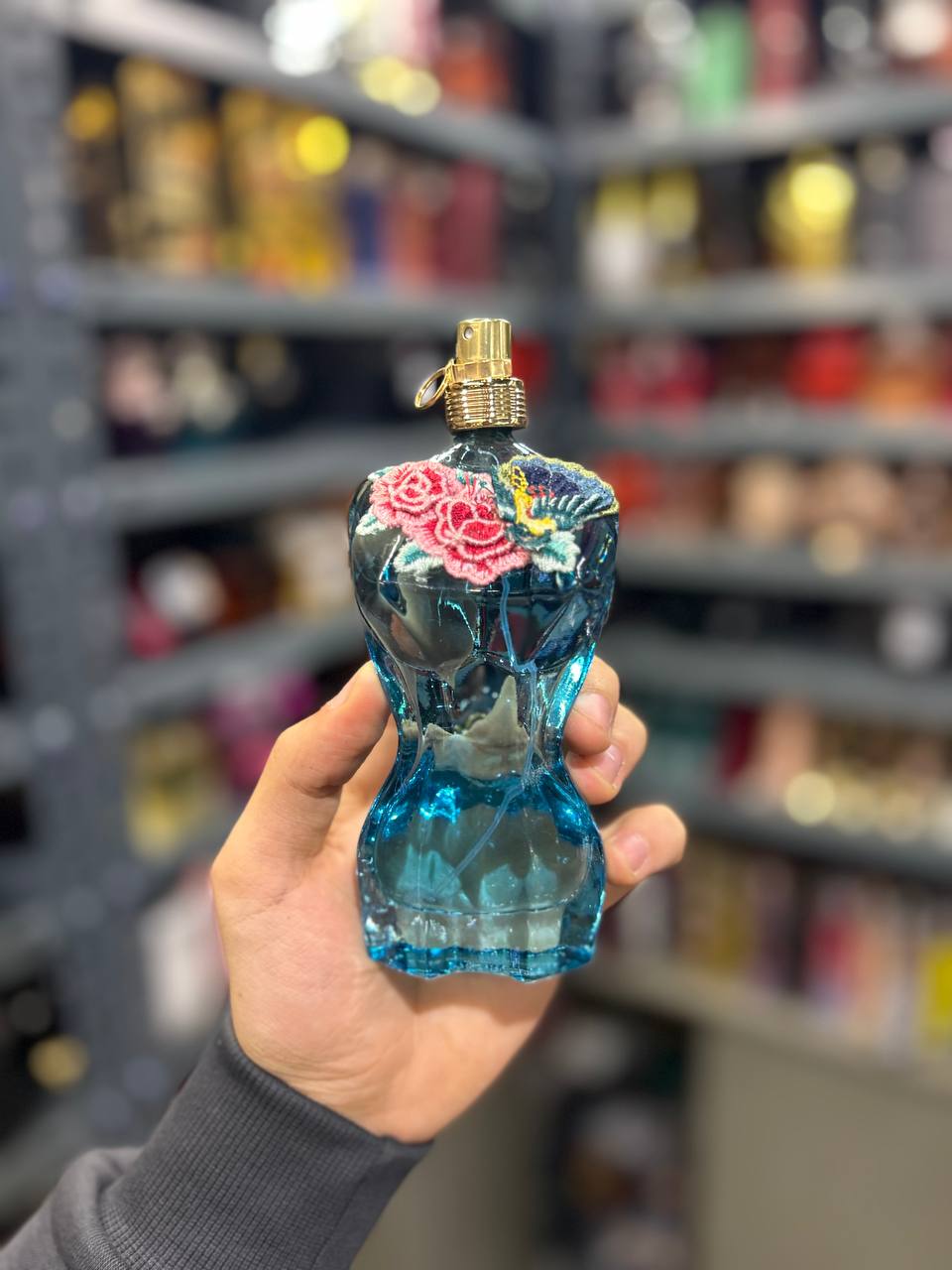 a person holding a blue glass perfume bottle in a store