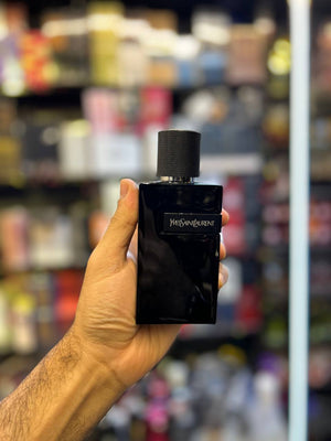 a hand holding a black bottle in a store