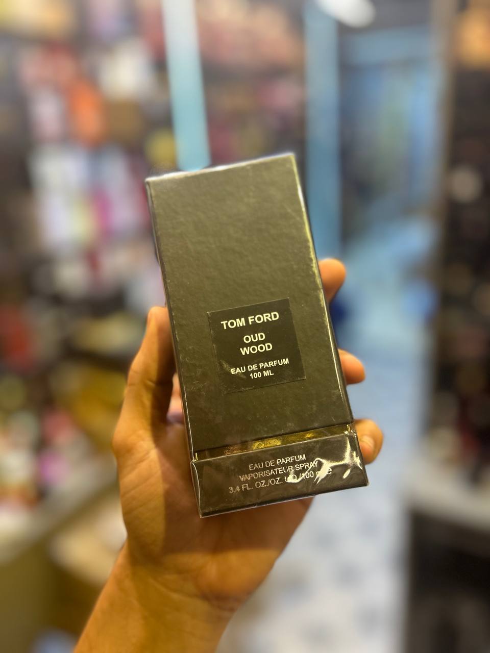 a person holding up a box of tom ford liquid