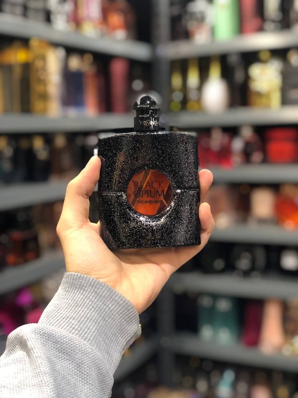 a person holding up a black flask in a store