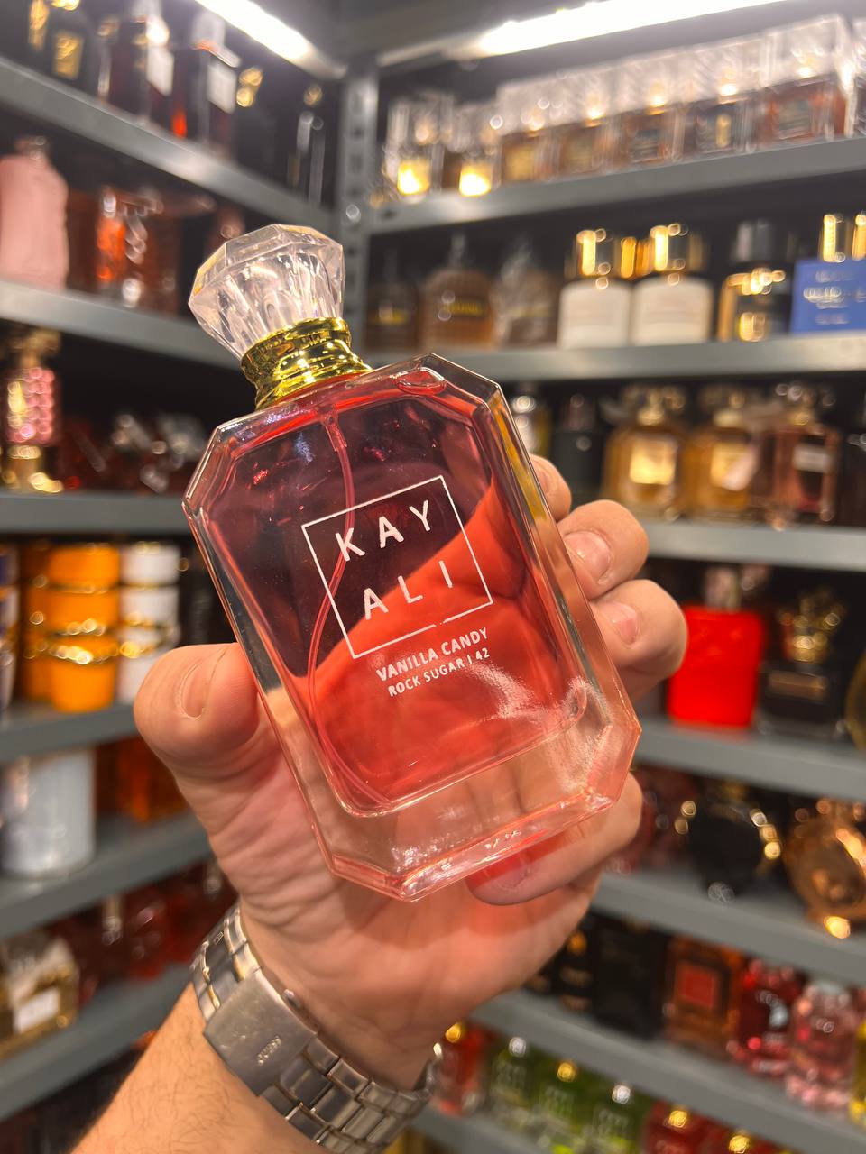 a person holding a bottle of kaly perfume in a store