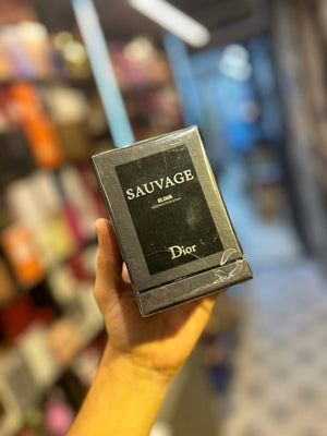 a hand holding a box of sauvage in a store