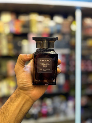 a hand holding a bottle of tom ford
