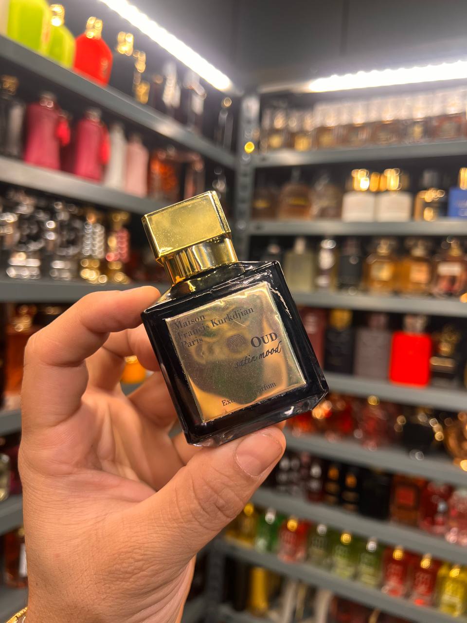 a person holding a small bottle of perfume in a store